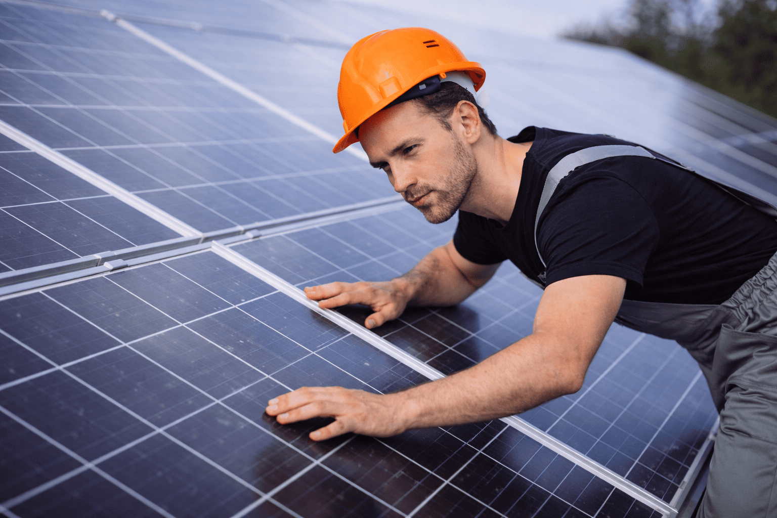 Monter solarnih fotonaponskih sustava u crnoj majici pregledava solarne panele na krovu.